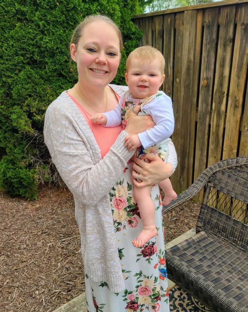Mom holding a baby in matching boutique summer dresses. 