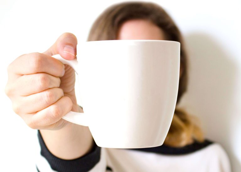 Woman holding out a coffee mug