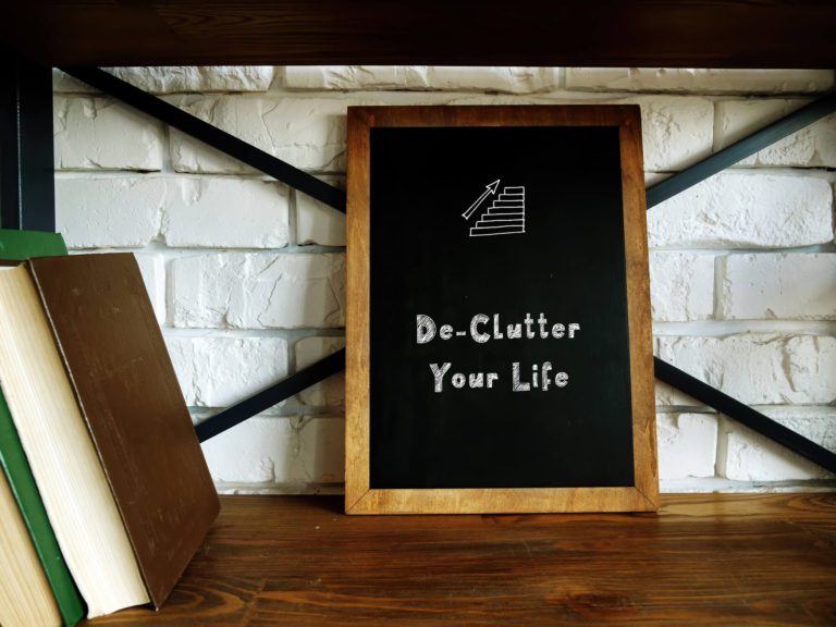 Declutter your life chalkboard sign on a bookshelf with the best books about decluttering!