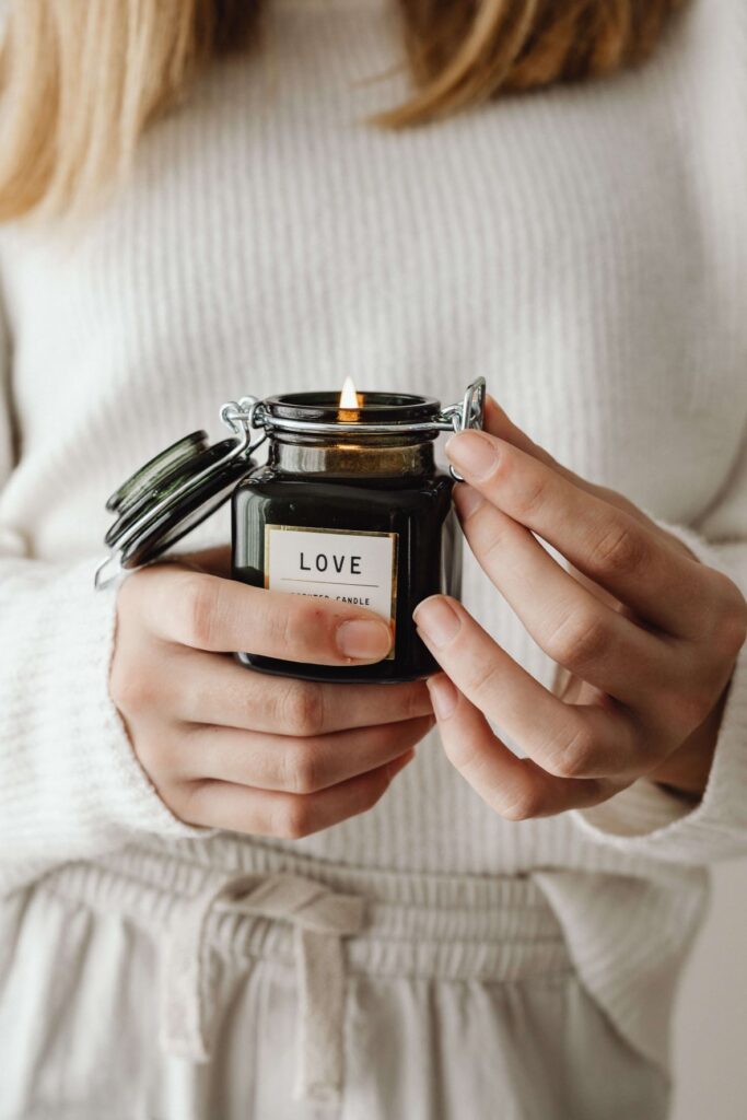 Woman holding a candle that says Love on the label