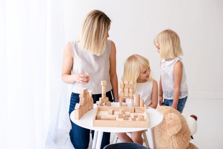 Mom sitting with her two children playing at a toddler table.