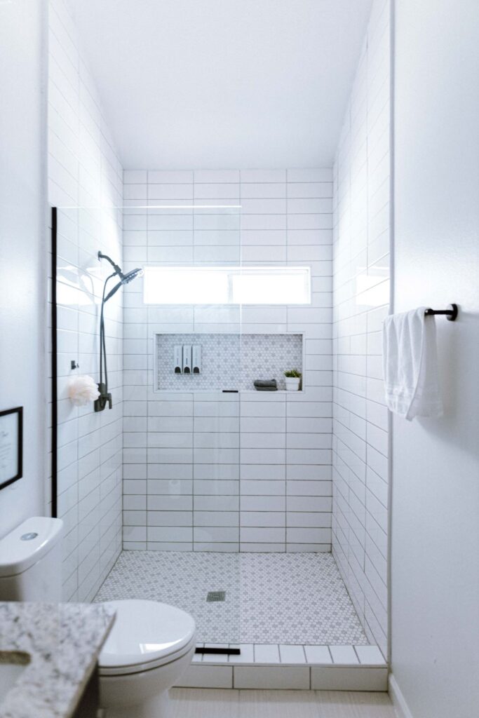 A white tiled bathroom with a shower. Showering is a great way of managing stress as a mom.