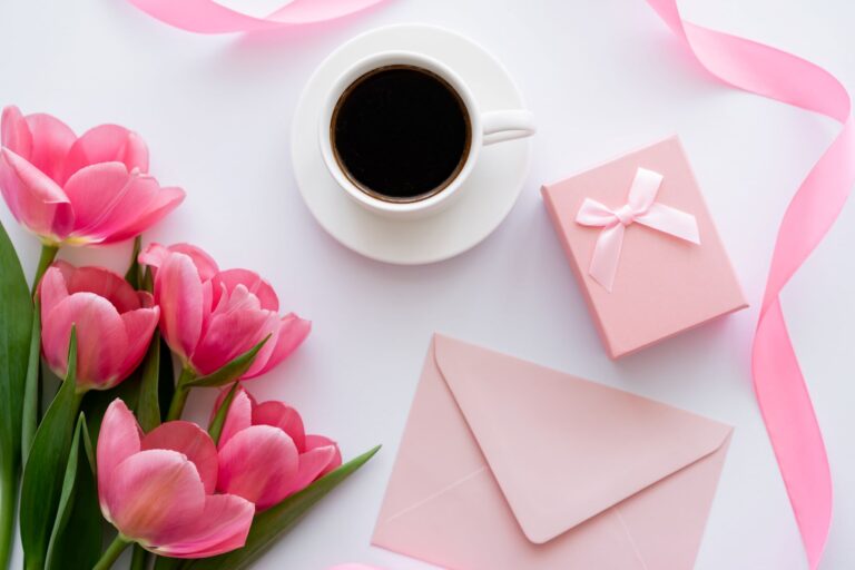 A cup of coffee for mom next to a gift box and a card and flowers.