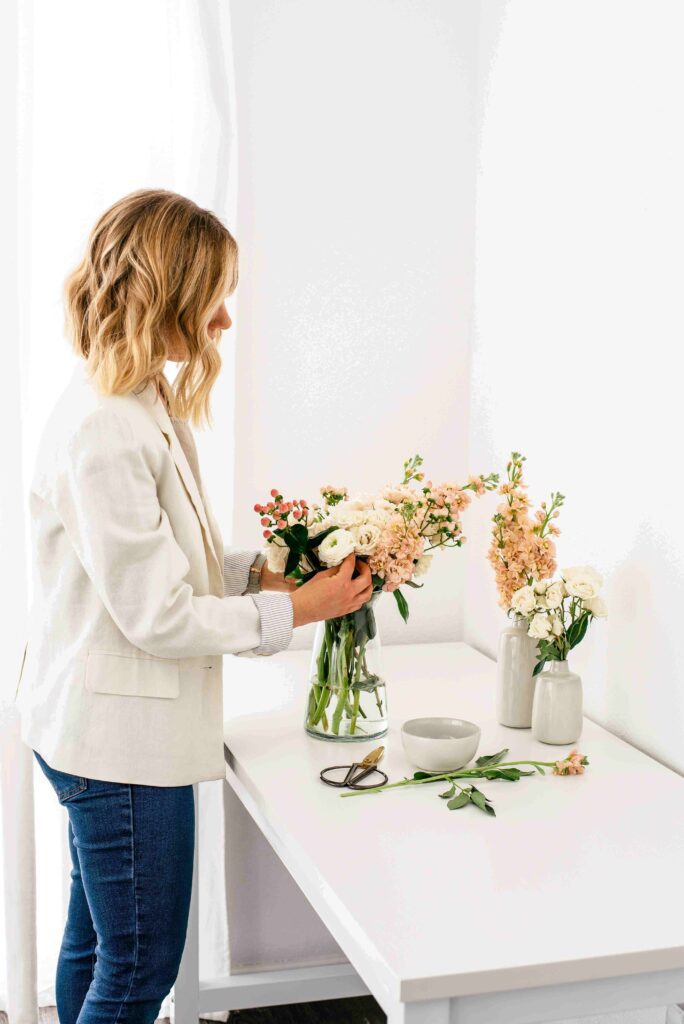 A woman arranging spring flowers in a vase. The perfect spring self-care idea.