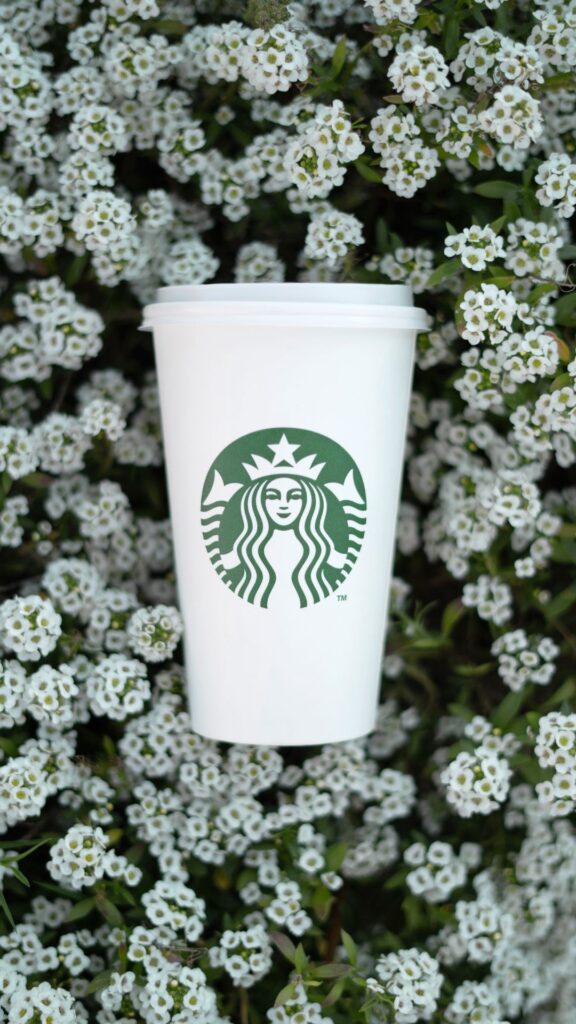 Starbucks cup laying on a bunch of flowers. 