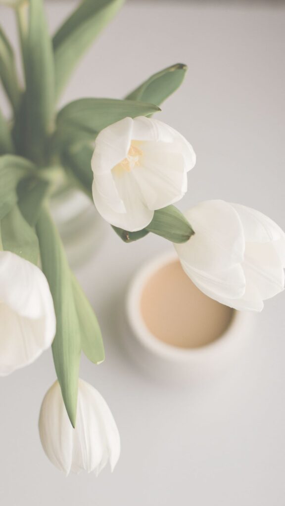 A cup of coffee behind some tulips makes for a great coffee phone wallpaper.
