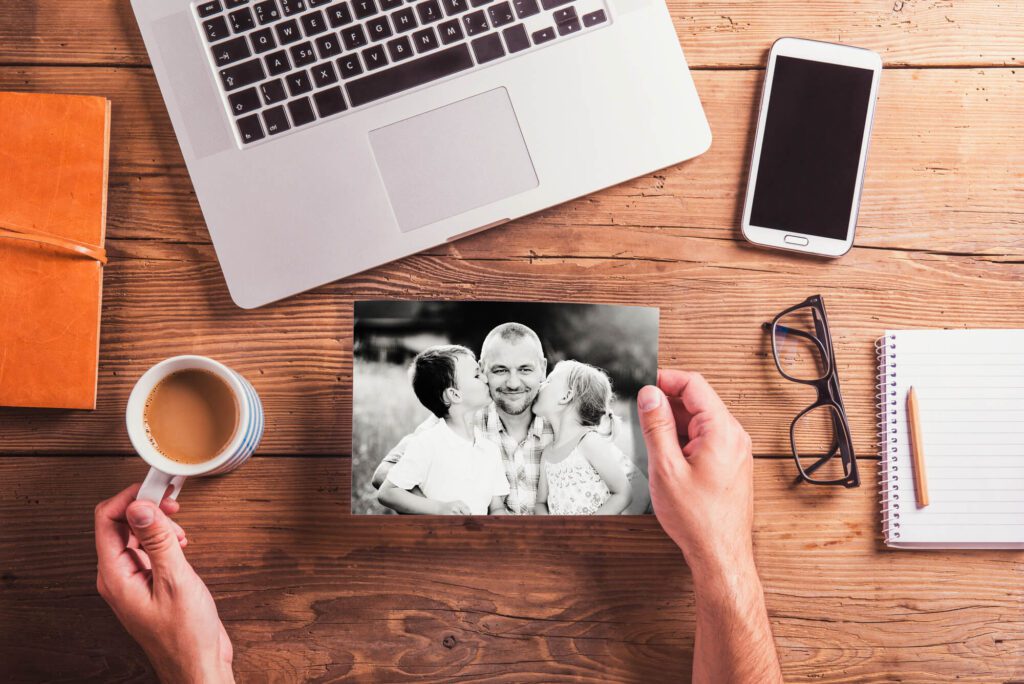 A picture of a dad with his kids and a cup of coffee and other office accessories in the background.