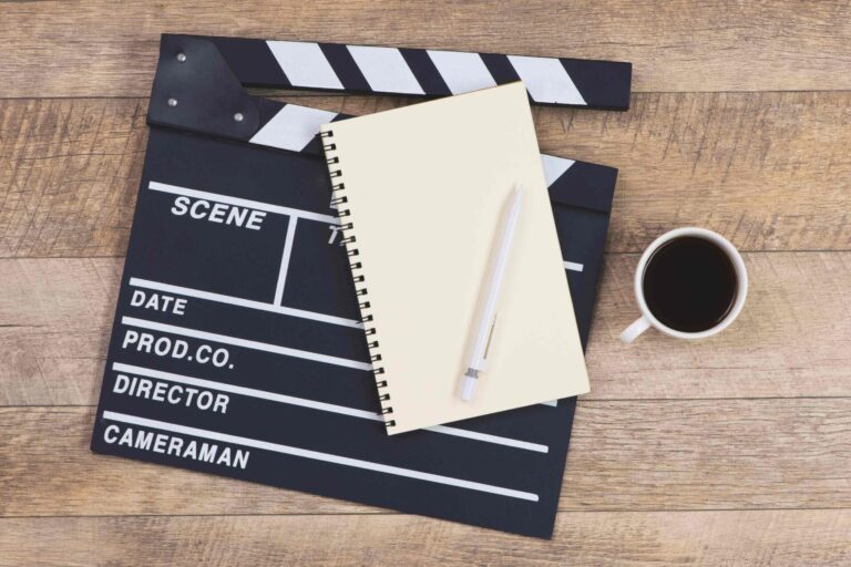 A cup of coffee next to a notepad and pen on top of a film clapboard.