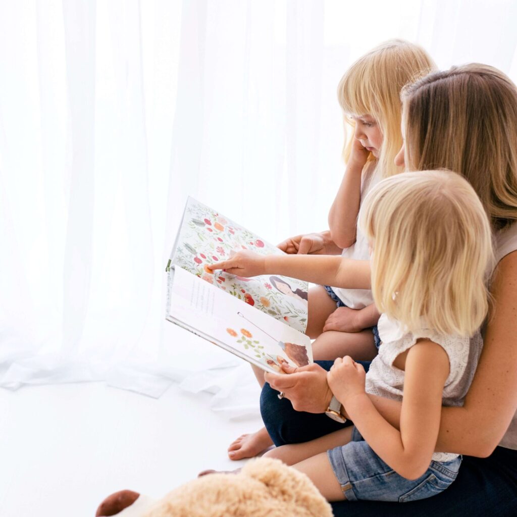 A mom reading a book to two children.