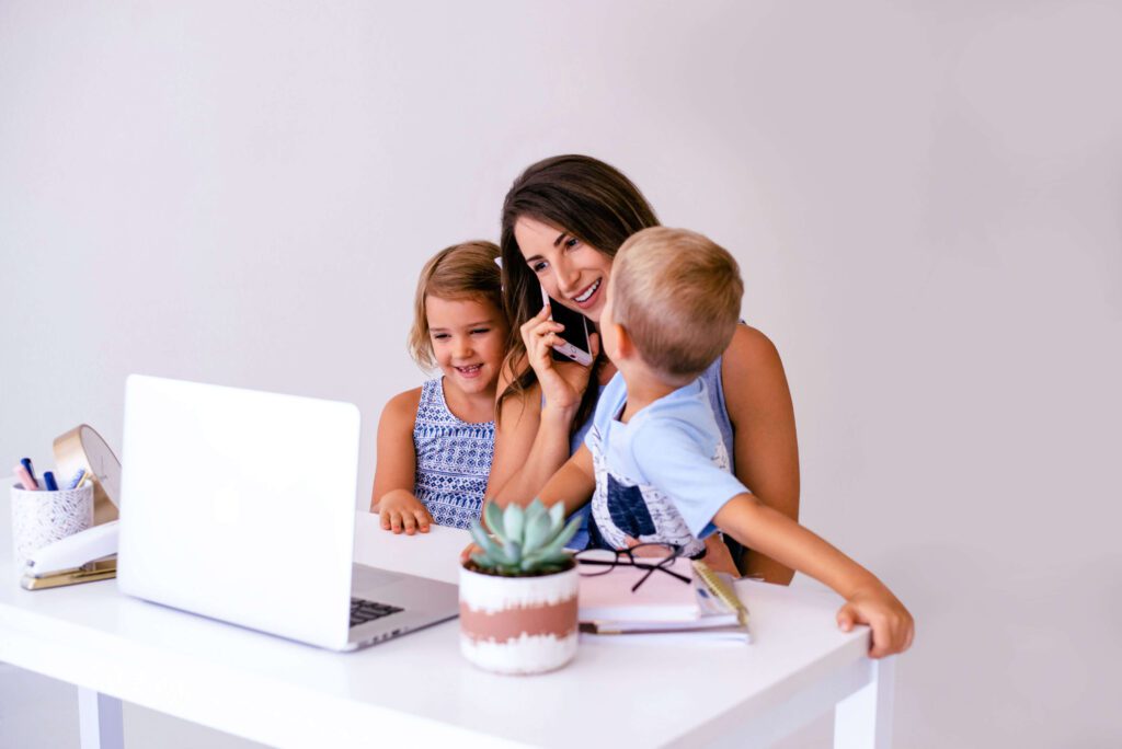 A mom working from home with kids around her while she talks on the phone.