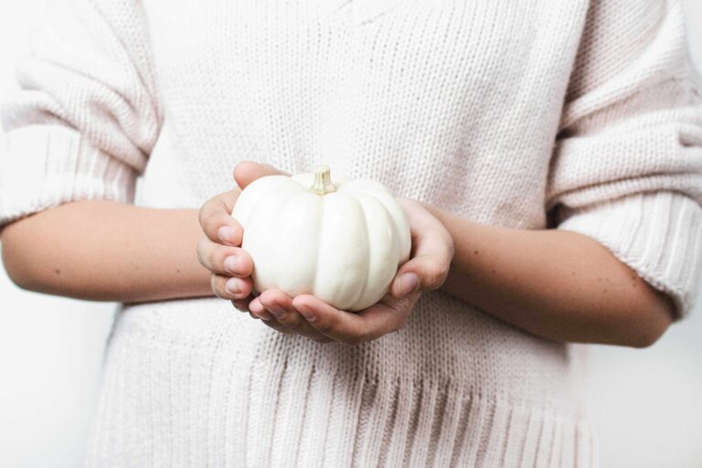 A woman holding a white pumpkin.