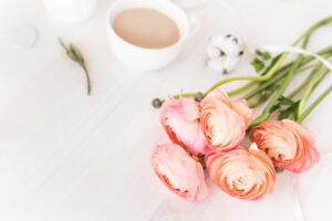 Flat lay of a cup of coffee next to pink flowers