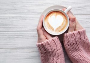 A woman with her hands around a cup of coffee, practicing slow living.