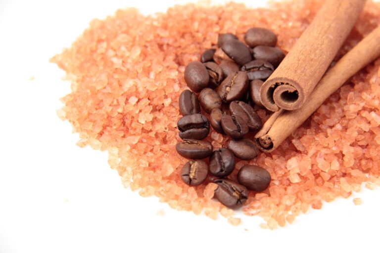 Coffee beans on top of salt next to cinnamon sticks.